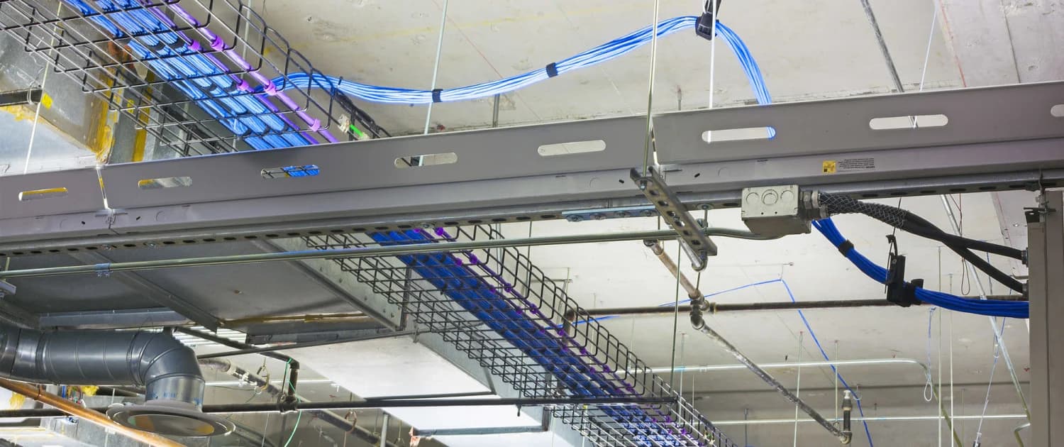 Technician pulling Cat6A cable above a finished commercial ceiling